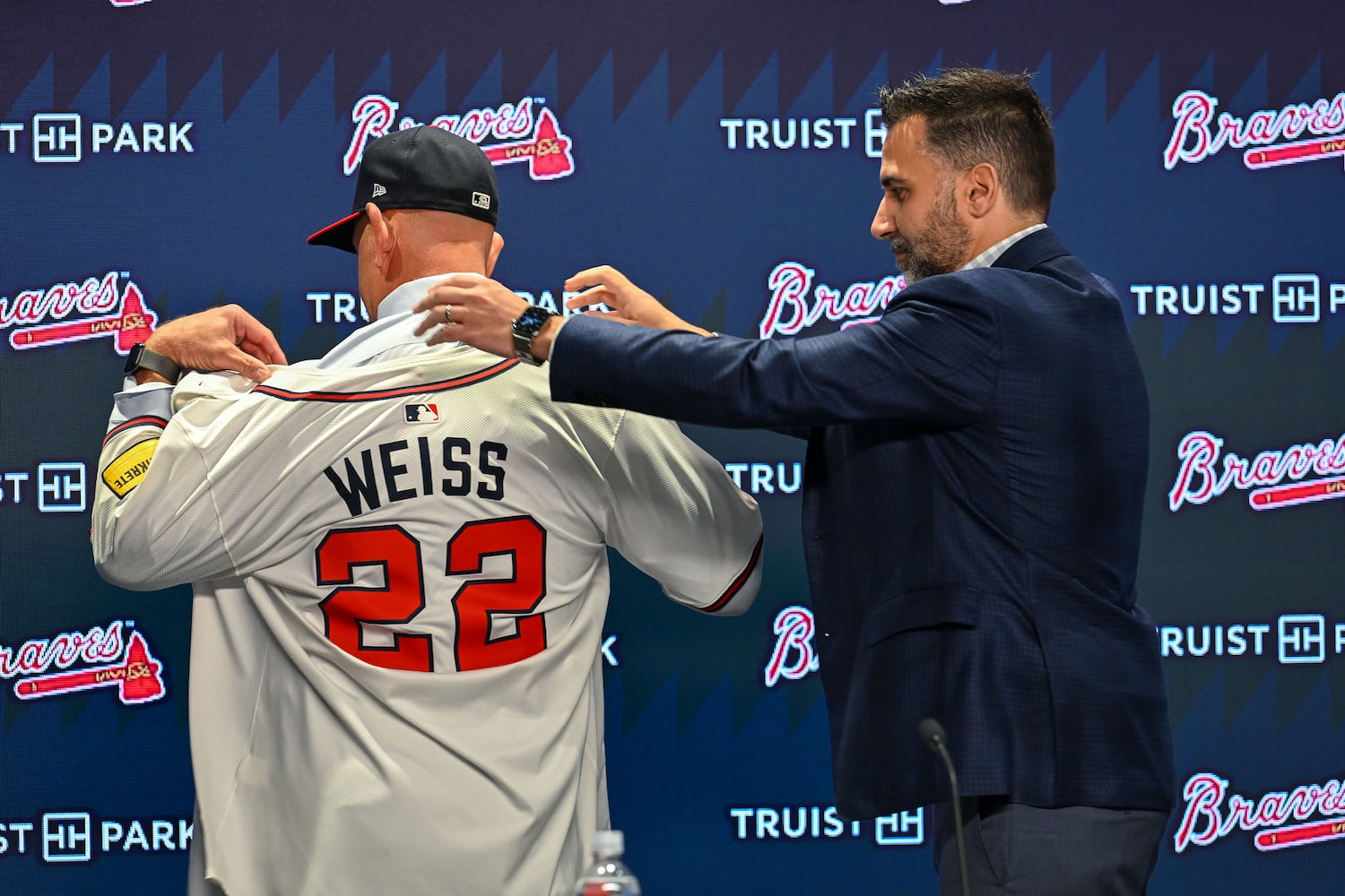 Newly hired Braves manager Walt Weiss tries on his new jersey with help from president of baseball operations Alex Anthopoulos during a news conference Tuesday, Nov. 4, 2025, at Truist Park in Atlanta. (Daniel Varnado for the AJC)