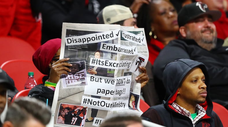 111821 Atlanta: A disappointed, frustrated, embarrassed Falcons fan covers her face with a newspaper as her team falls 25-0 to the Patriots in a NFL football game on Thursday, Nov. 18, 2021, in Atlanta. “Curtis Compton / Curtis.Compton@ajc.com”