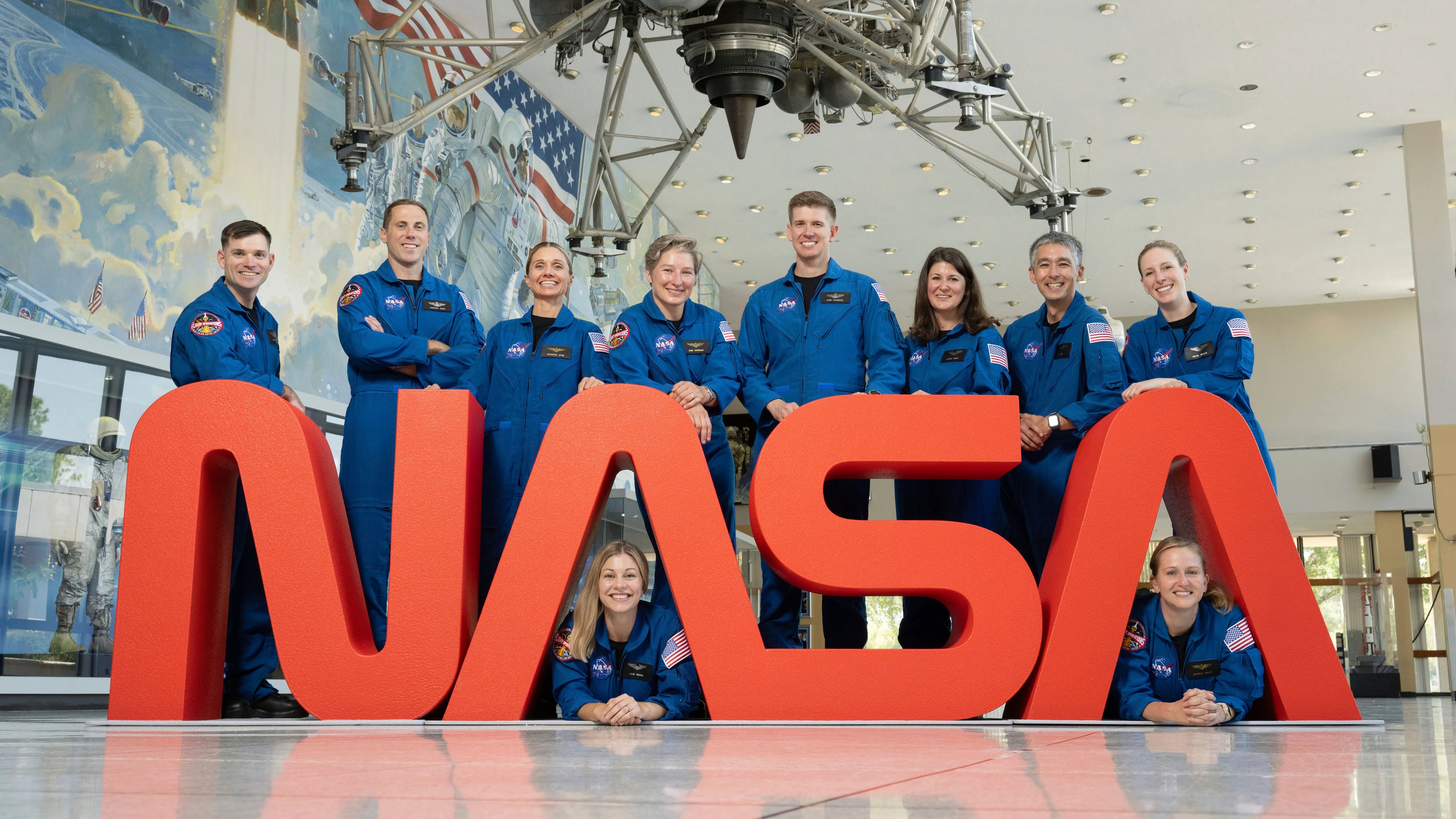 In this undated photo released by NASA, NASA's 10 newest astronauts pose behind the logo at at NASA’s Johnson Space Center in Houston, Texas. Left to right; Sept. 22, 2025. The 10 candidates, pictured here at NASA’s Johnson Space Center in Houston. U.S. Army CW3 Ben Bailey, U.S. Air Force Maj. Cameron Jones, Katherine Spies, Anna Menon, U.S. Navy Lt. Cmdr. Erin Overcash, U.S. Air Force Maj. Adam Fuhrmann, Lauren Edgar, Yuri Kubo, Rebecca Lawler, and Dr. Imelda Muller. (NASA via AP)