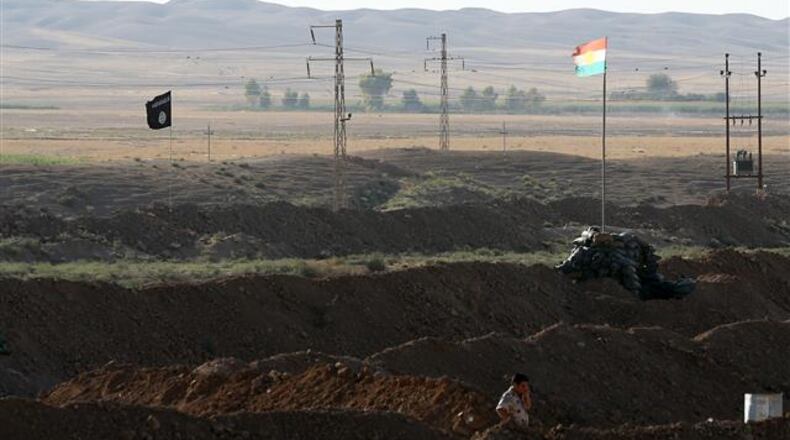 A Kurdish Peshmerga stands at the front line with the Islamic State group, their trademark black flags are seen and Kurdish flags in the background, in Kirkuk, 290 kilometers (180 miles) north of Baghdad, Iraq, Saturday, Sept. 27, 2014. The tense standoff frustrates many of the young soldiers, away from their families now for several months, even as other units make gains with the help of U.S. and French airstrikes. (AP Photo/Hadi Mizban) The battlefield in Iraq features the flags of two non-nations. The black Islamic State flag (left) and the Kurds (right). (AP Photo)
