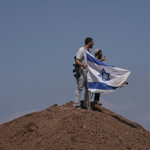 Israeli settlers put up an Israeli flag on a hilltop after it was taken down by Israeli and foreign peace activists during a protest in support of local landowners whose property is threatened with seizure by settlers, on the outskirts of the West Bank city of Beit Sahour, Friday, Aug. 14, 2026. (AP Photo/Mahmoud Illean)