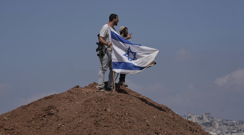 Israeli settlers put up an Israeli flag on a hilltop after it was taken down by Israeli and foreign peace activists during a protest in support of local landowners whose property is threatened with seizure by settlers, on the outskirts of the West Bank city of Beit Sahour, Friday, Aug. 14, 2026. (AP Photo/Mahmoud Illean)