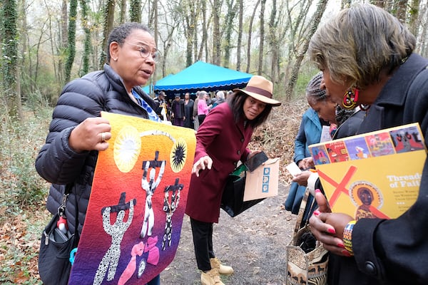 Juandamarie Gikand (left) shows a replica of a Harriet Powers quilt after the 2023 dedication ceremony of a new headstone for Harriet and Armstead Powers. The quiltmaker’s works are celebrated as masterpieces of folk art and storytelling. (Nell Carroll for the AJC)