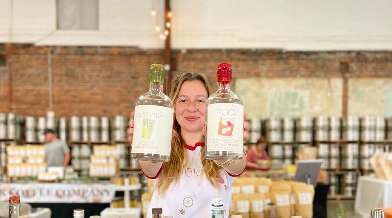 Marguerite Seckman holds up several different cocktail bottles while at the Makers Market.
