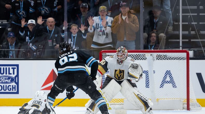 Vegas Golden Knights goalkeeper Carl Lindbom, right, prepares to defend a shot on goal as Utah Mammoth center Logan Cooley, center, takes the puck downice during the third period of an NHL hockey game, Monday, Nov. 24, 2025, in Salt Lake City. (AP Photo/Anna Fuder)