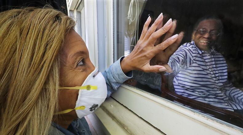Camilla White visits her mother Lillian Barber, 90, from outside seeing her through the window while touching fingertips through the glass at Cottage Landing Assisted Living on Tuesday, April 28, 2020, in Carrollton. White didn’t discover there had been several deaths at the home from coronavirus and a significant outbreak until seeing the info on a state website and said that before the outbreak, “I would go inside and just lay my head in her lap, but I can’t do none of that anymore.” (Curtis Compton / ccompton@ajc.com)
