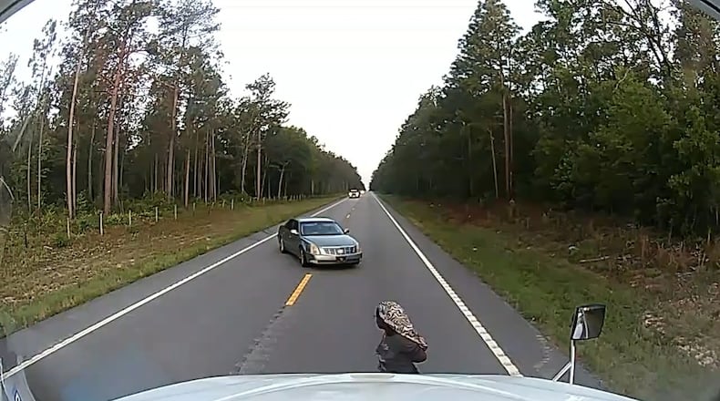 In this frame grab from a dashboard camera video, a cuffed woman is seen running away from her alleged kidnapper near Aiken, S.C., on Friday, May 29, 2026. (Anthony J. Moore via AP)