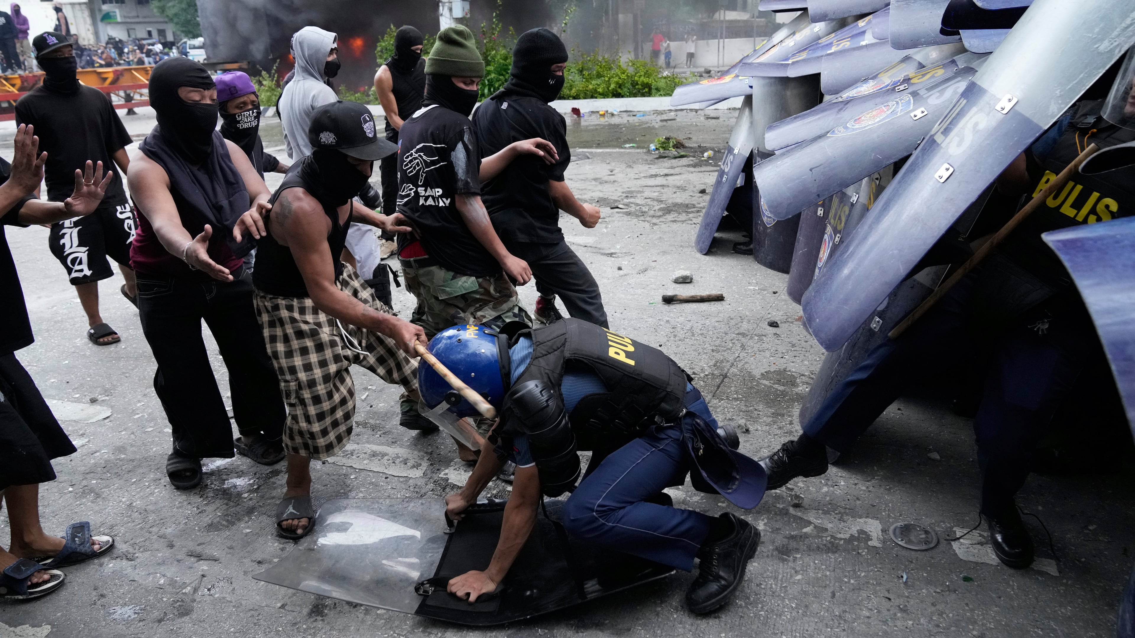 A protester hits police during a scuffle as they tried to enter the Malacanang palace compound in Manila, Philippines on Sunday, Sept. 21, 2025. (AP Photo/Aaron Favila)