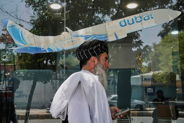 An Afghan man passes in front of an air travel agency in Kabul, Afghanistan, Thursday, June 5, 2025. (AP Photo/Ebrahim Noroozi)
