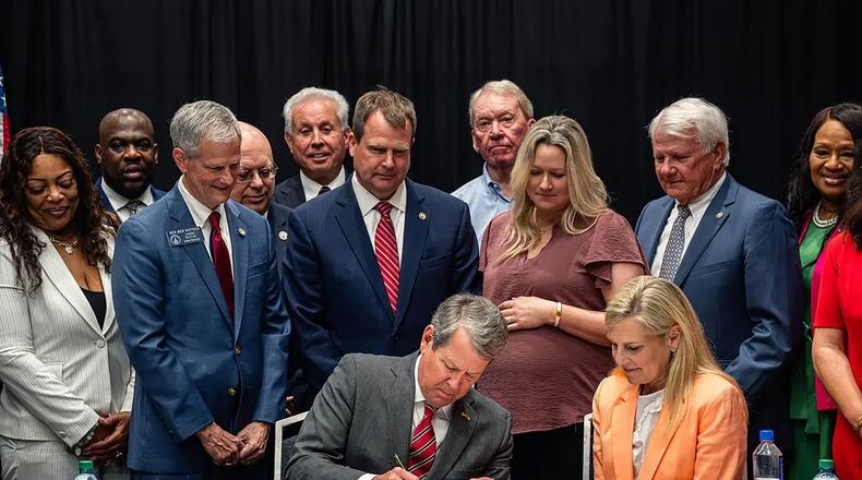 Governor Brian Kemp signs HB 428 at the Savannah Convention Center on May 1, 2025. House Bill 428 codifies the right to in vitro fertilization. Rep. Lehman Frankilin and his wife, Lorie, watch the signing. (Justin Taylor / The Current GA)