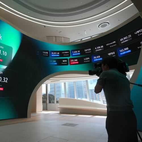 A TV cameraman films the screens showing the Korea Composite Stock Price Index (KOSPI) and the foreign exchange rate between U.S. dollar and South Korean won at a dealing room of Hana Bank in Seoul, South Korea, Thursday, June 18, 2026. (AP Photo/Lee Jin-man)