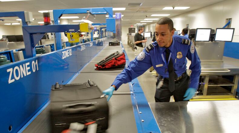 An officer in Hartsfield-Jackson’s baggage inspection room pulls a bag that was flagged for a physical check. A project for a new system at the world’s busiest airport has generated a contracting dispute. Bob Andres bandres@ajc.com