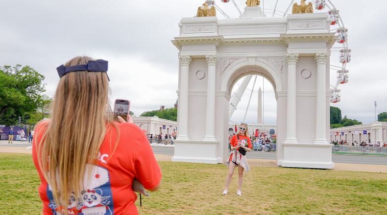 Visitors take photos at the Great American State Fair on the National Mall, with the ferris wheel and a model of the triumphal arch in the background, Thursday, July 9, 2026, in Washington. (AP Photo/Mariam Zuhaib)