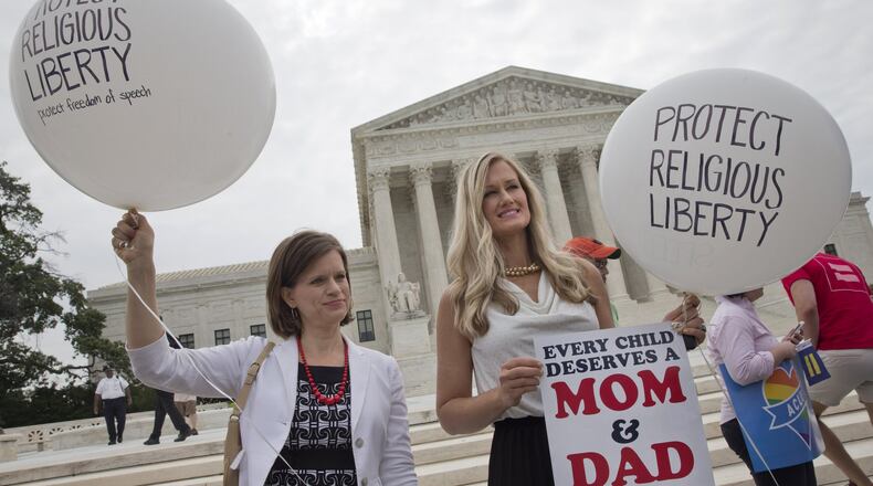 Jennifer Marshall, with the Heritage Foundation, and Summer Ingram, with the Congressional Prayer Caucus Foundation, who said they support “traditional marriage” hold balloons that says “protect religious liberty” outside of the Supreme Court Friday June 26, 2015, in Washington, before the court declared that same-sex couples have a right to marry anywhere in the US. (AP Photo/Jacquelyn Martin)