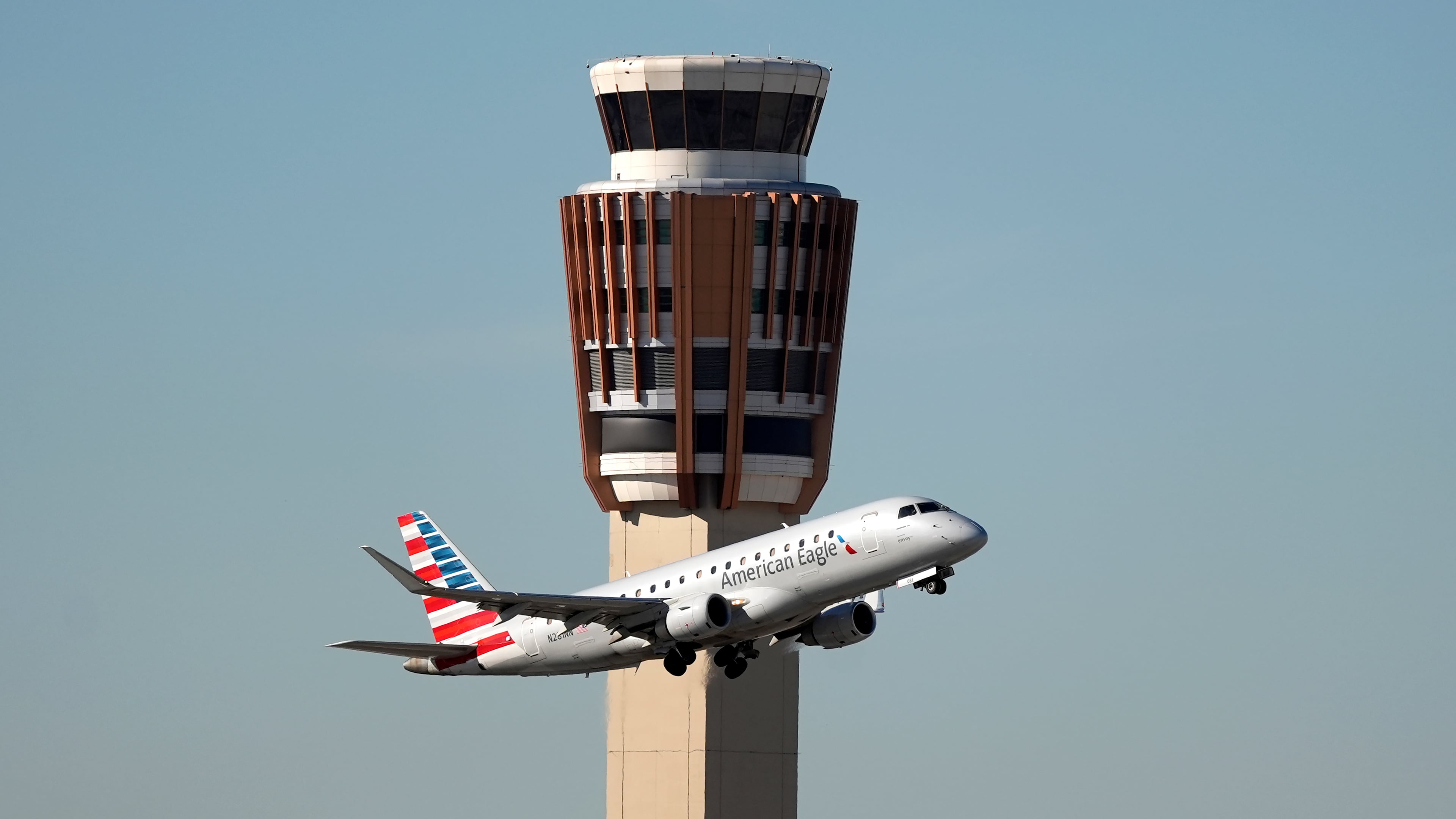 An American Airlines American Eagle jet flies past the air traffic control tower at Phoenix Sky Harbor International Airport Saturday, Nov. 8, 2025, in Phoenix. (AP Photo/Ross D. Franklin)