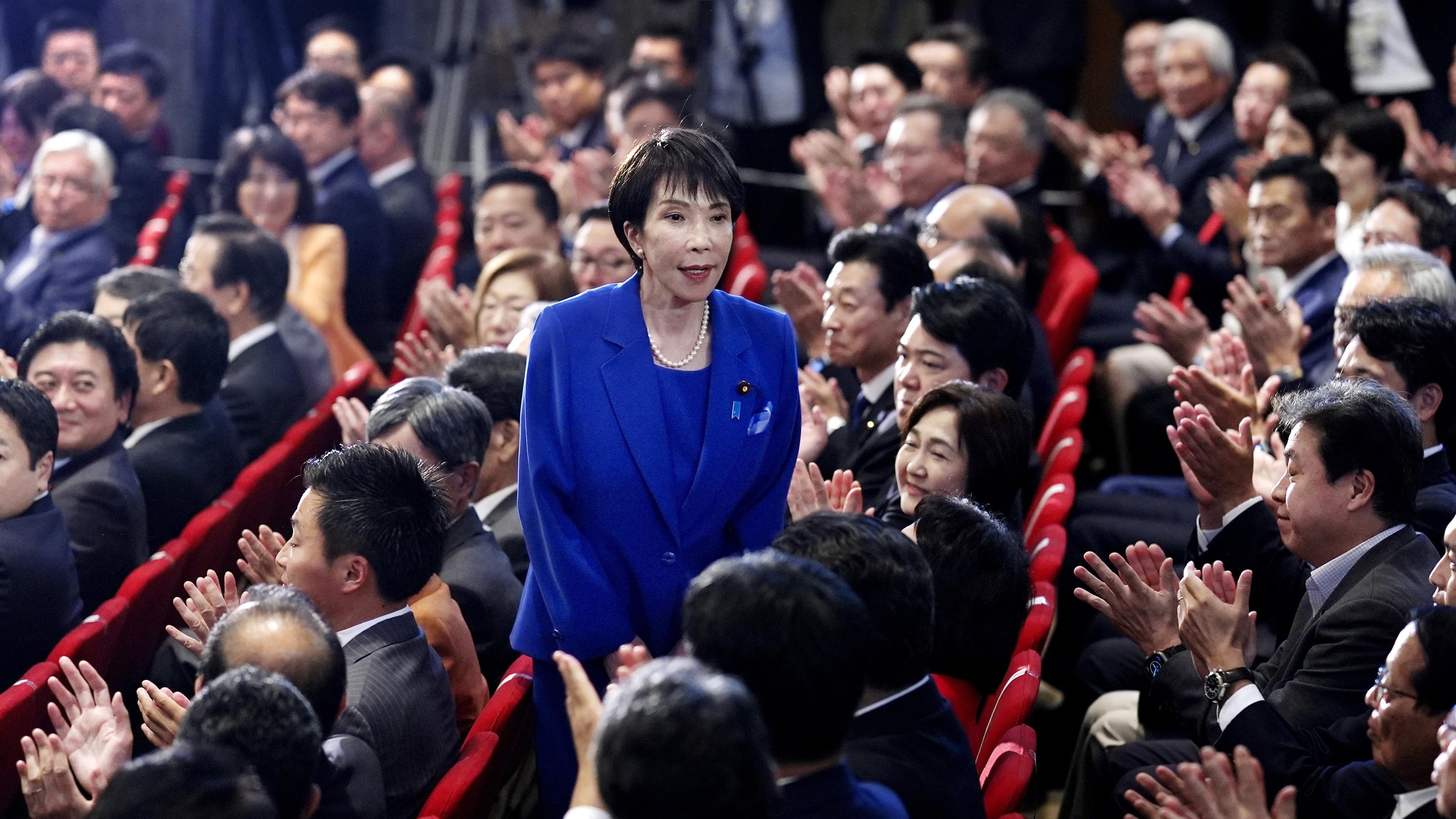 Former Economic Security Minister Sanae Takaichi, center, stands as Takaichi was chosen to a new leader of Japan’s ruling Liberal Democratic Party during the party's leadership election in Tokyo, Japan, Saturday, Oct. 4, 2025. (Kyodo News via AP)