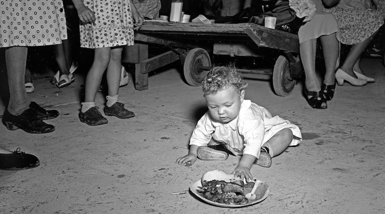 The Atlanta History Center exhibition “Barbecue Nation” explores the appeal of barbecue through American history and artifacts, including this 1940s photograph of a tobacco warehouse opening in Florida. CONTRIBUTED BY ATLANTA HISTORY CENTER