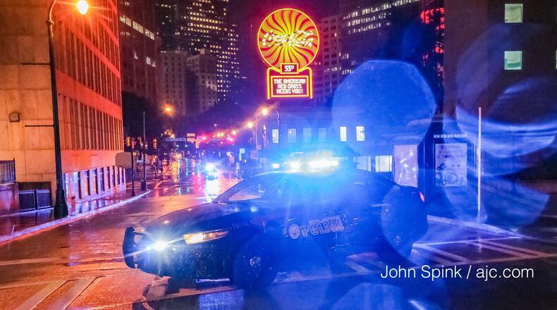 A city police car blocks Peachtree Street in downtown Atlanta on Monday after debris fell off a high-rise building near Woodruff Park. JOHN SPINK / JSPINK@AJC.COM