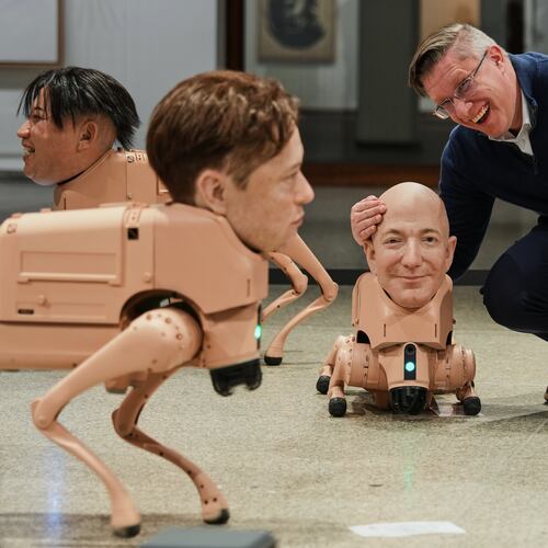Artist Beeple, Mike Winkelmann, poses inside his installation titled Regular Animals, with robots in the likeness of Kim Jong Un, left, Elon Musk, second left, Kim Jong Un, Jeff Bezos, center, and Mark Zuckerberg, right, at the Neue Nationalgalerie museum in Berlin, Germany, Tuesday, April 28, 2026. (AP Photo/Markus Schreiber)