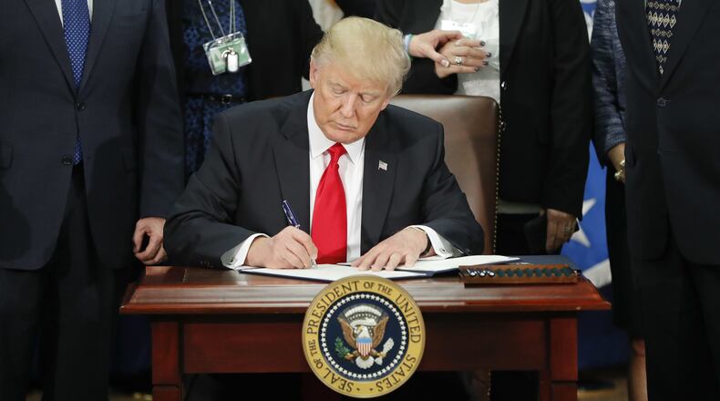 In this Jan. 25, 2017, photo President Donald Trump signs an executive order for border security and immigration enforcement improvements at the Department of Homeland Security in Washington. Two days later, he signed a separate executive order temporally blocking travelers from seven predominantly Muslim countries and halting the resettlement of refugees in the U.S. (AP Photo/Pablo Martinez Monsivais)