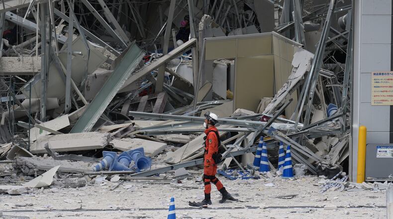 A rescue worker walks in front of AEON Mall, which was damaged by an explosion following an earthquake, is seen in Kashima, Kumamoto Prefecture, southern Japan, Wednesday, July 29, 2026. (AP Photo/Hiro Komae)