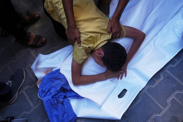 A Palestinian boy mourns over the body of his 12-year-old friend, Abdullah Ahmed, who was killed in an Israeli strike that targeted a drinking water distribution point, at Al-Awda Hospital in Nuseirat, central Gaza Strip, Sunday, July 13, 2025. (AP Photo/Abdel Kareem Hana)