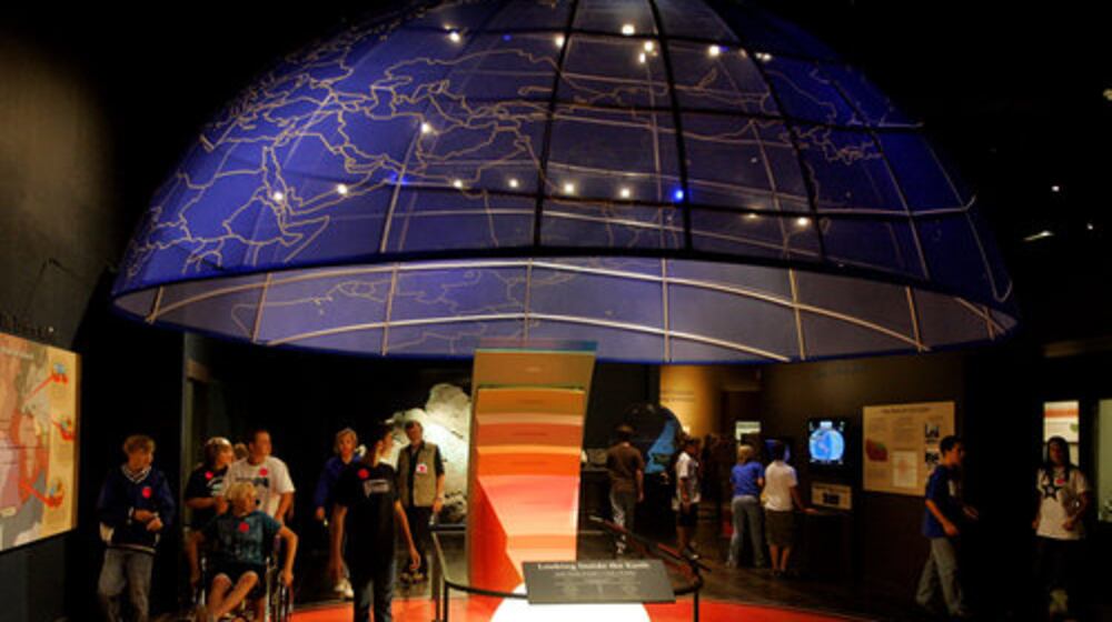 A school group walks through a cutaway view of the layers under the earth.