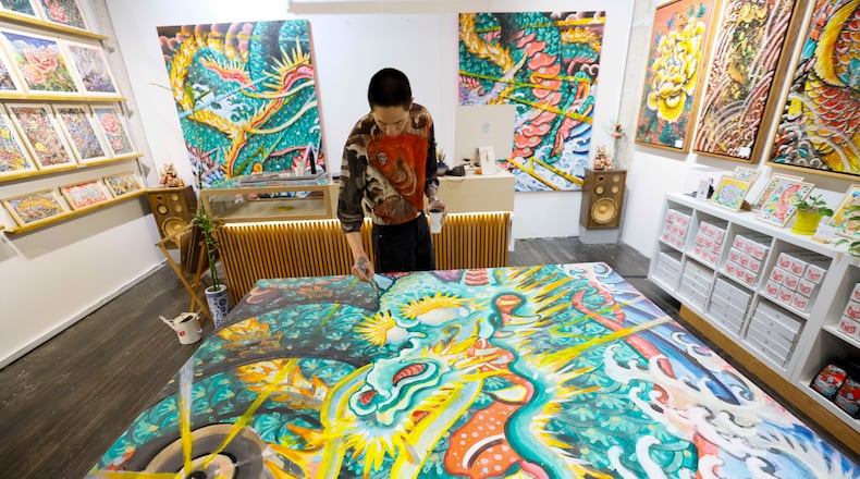 Andrew Blooms — shown working on a large painting at Blooms Emporium, his gallery-shop at Ponce City Market — has begun organizing monthly Blooms Chinatown Market events at Chamblee's Chinatown Mall. (Miguel Martinez/AJC)