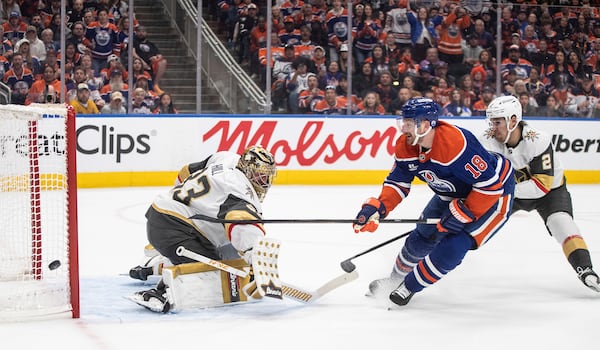 Vegas Golden Knights goalie Adin Hill (33) makes a save against Edmonton Oilers' Zach Hyman (18) as Golden Knights' Zach Whitecloud (2) defends during the second period of Game 4 of a second-round NHL hockey playoff series in Edmonton, Alberta, Monday, May 12, 2025. (Jason Franson/The Canadian Press via AP)