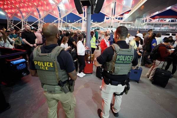 Federal ICE agents assist TSA operations while travelers line up for security at Hartsfield-Jackson Atlanta International Airport on Monday. ICE agents will not carry out immigration enforcement during this deployment, according to Atlanta Mayor Andre Dickens. (Miguel Martinez/AJC)