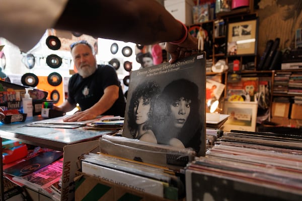 Wax ’n’ Facts customers sift through vinyl albums near the checkout counter, including a Donna Summer/Barbara Streisand collab "No More Tears." (Estela Muñoz/AJC)