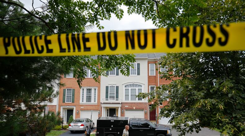 A law enforcement officer walks on the street outside the home of Nicholas Young, a Washington Metro Transit Officer, Wednesday, Aug. 3, 2016, in Fairfax, Va., Young was arrested at Metro's headquarters in Washington and charged with a single count of attempting to provided material support to a terrorist group. (AP Photo/Pablo Martinez Monsivais)