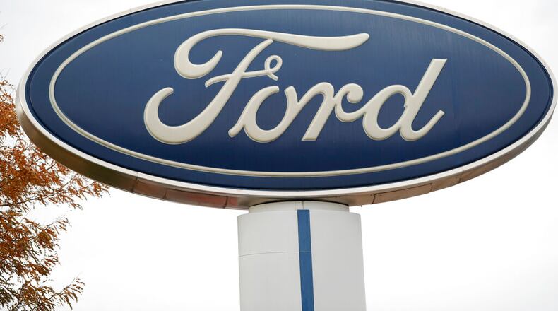 FILE - In this Oct. 20, 2019, file photo, the company logo stands over a long row of unsold vehicles at a Ford dealership in Littleton, Colo. Ford is recalling about 2.5 million vehicles in the U.S., Canada and elsewhere because of a nagging door latch problem and a brake fluid leak. The door latch recall covers more than 2.1 million cars, SUVs and vans in the U.S. The latches can fail and cause the doors to open while the vehicles are moving. It's the third recall for the same problem. (AP Photo/David Zalubowski, File)