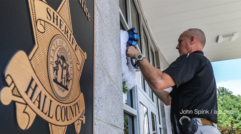 Hall County Sheriff's Deputy T. Ambercrombie hangs wreaths in front of the sheriff's office on Monday. A deputy died after a Sunday night shootout with suspects believed to be linked to recent break-ins and robberies. AJC photo: John Spink