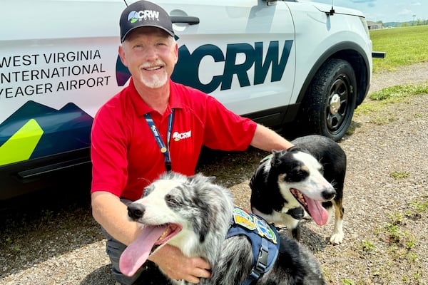 West Virginia International Yeager Airport wildlife specialist and dog handler Chris Keyser poses with Hercules and Ned at the airport in Charleston, W.Va. (AP Photo/John Raby)