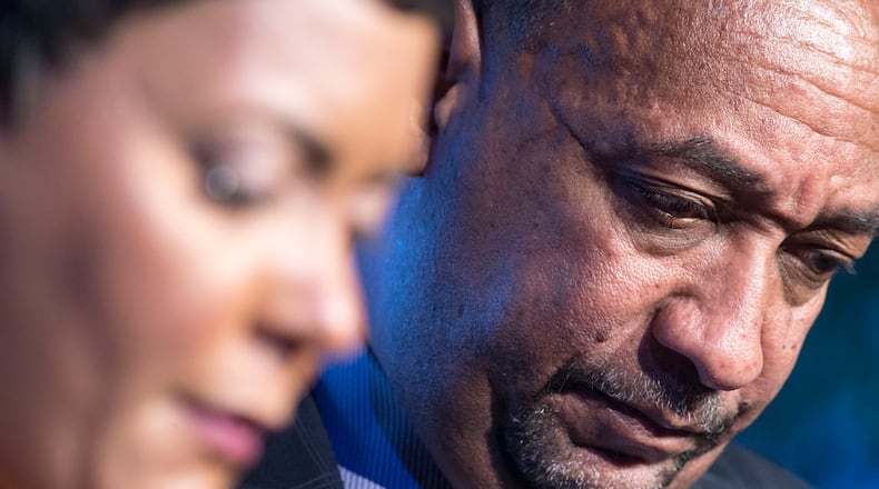 Derek Bottoms, right, and his wife, Atlanta Mayor Keisha Lance Bottoms hold their heads in reverence as faith leaders pray over their family during the inaugural interfaith worship service held at Impact Church in East Point on Jan. 2.