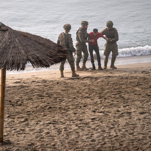Spanish army soldiers assist a migrant who swam from Morocco to the Spanish enclave of Ceuta, Saturday, Aug. 1, 2026. (AP Photo/Antonio Sempere)