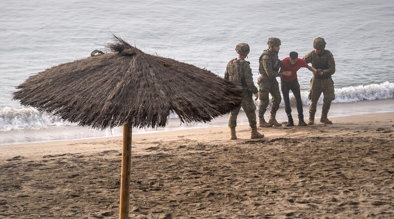 Spanish army soldiers assist a migrant who swam from Morocco to the Spanish enclave of Ceuta, Saturday, Aug. 1, 2026. (AP Photo/Antonio Sempere)