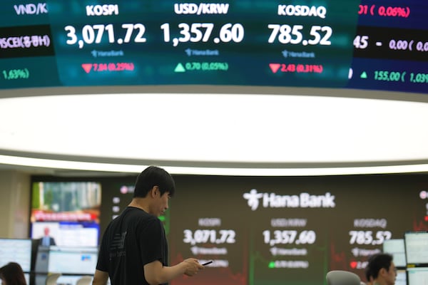 A dealer walks past near screens showing the Korea Composite Stock Price Index (KOSPI), left, the foreign exchange rate between U.S. dollar and South Korean won and South Korean won and the Korean Securities Dealers Automated Quotations (KOSDAQ) at a dealing room of Hana Bank in Seoul, South Korea, Friday, June 27, 2025. (AP Photo/Lee Jin-man)