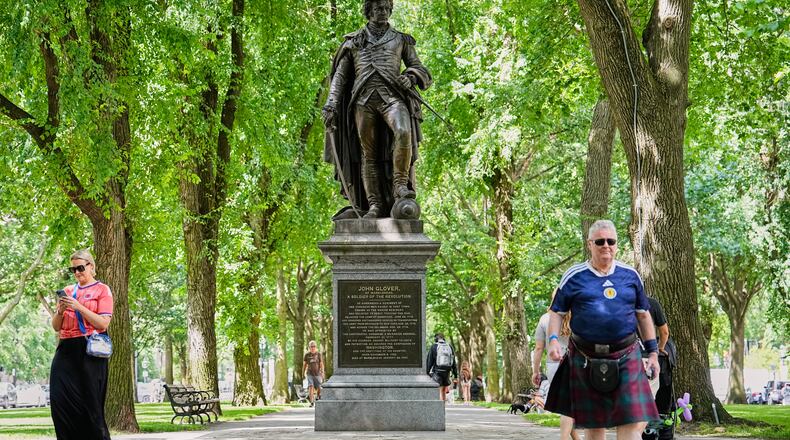 Scottish fans passing a statue of the revolutionary John Glover, humorously decorated with a traffic cone, in a park in Boston, Mass., ahead of the World Cup Group C soccer match between Scotland and Morocco, Friday, June 19, 2026. (AP Photo/Martin Meissner)