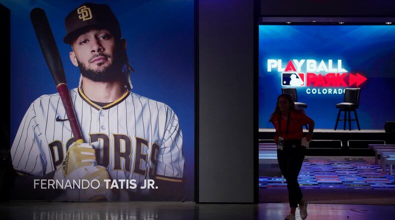 A worker runs out of the clubhouse exhibit and past a photograph of San Diego Padres shortastop Fernando Tatis Jr. at the Play Ball Park exhibit at the Colorado Convention Center staged by Major League Baseball as part of the festivities leading up to the All Star Game Friday, July 9, 2021, in Denver. The convention center has been turned into a paradise for baseball aficionados complete with batting cages, an onsite home run derby, items from the Hall of Fame and countless merchandise for sale for baseball fans from far and near at the store.