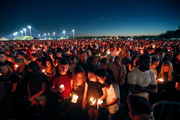 FILE - People attend a candlelight vigil for the victims of a shooting at Marjory Stoneman Douglas High School, in Parkland, Fla., Feb. 15, 2018. (AP Photo/Gerald Herbert, File)
