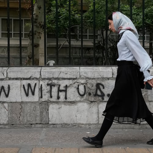 A woman walks past an anti-U.S. graffiti painted on the wall of the Tehran University on Enqelab-e-Eslami (Islamic Revolution) street in downtown Tehran, Iran, Saturday, April 25, 2026. (AP Photo/Vahid Salemi)