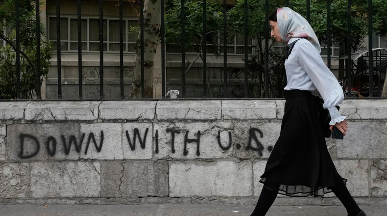A woman walks past an anti-U.S. graffiti painted on the wall of the Tehran University on Enqelab-e-Eslami (Islamic Revolution) street in downtown Tehran, Iran, Saturday, April 25, 2026. (AP Photo/Vahid Salemi)