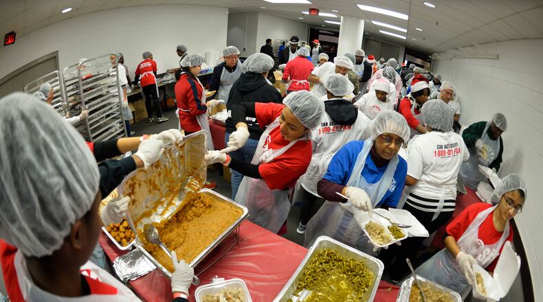 HOSEA FEED THE HUNGRY DINNER--Nikki Dedani, center, helps some of the more than 2,000 volunteers prepare meals for an expected 5,000 homeless people during the annual Hosea Feed the Homeless Christmas dinner at the Georgia World Congress Center on Thursday, Dec. 25, 2014, in Atlanta. Spokesperson Quisa Foster said the volunteer crew makes an additional 5,000 dinners to be delivered to shut-ins, assisted living facilities and hospitals in the metro area. David Tulis/AJC Special