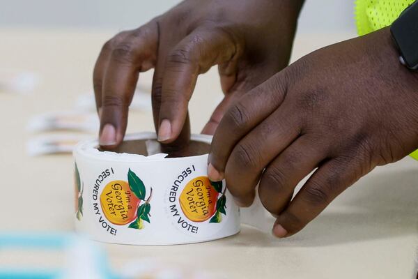 A poll worker readies voter stickers for distribution at the Ron Anderson Community Center in Powder Springs, Ga. last year. (Miguel Martinez/AJC 2025)