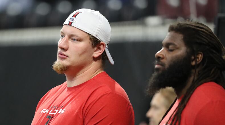 Falcons offensive tackle Kaleb McGary (left), recovering from heart surgery, watches from the sidelines as his team prepares to play the New York Jets. Curtis Compton/ccompton@ajc.com