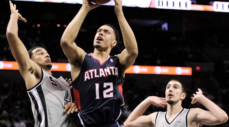Atlanta Hawks' John Jenkins (12) shoots against San Antonio Spurs' Cory Joseph, left, and Nando De Colo, of France, during the second half of an NBA basketball game, Saturday, April 6, 2013, in San Antonio. San Antonio won 99-97. (AP Photo/Darren Abate)