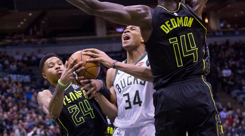 Milwaukee Bucks forward Giannis Antetokounmpo, center, is defended by Atlanta Hawks guard Kent Bazemore, left, and Dewayne Dedmon, right, during the first half of an NBA basketball game Tuesday, Feb. 13, 2018, in Milwaukee. (AP Photo/Darren Hauck)
