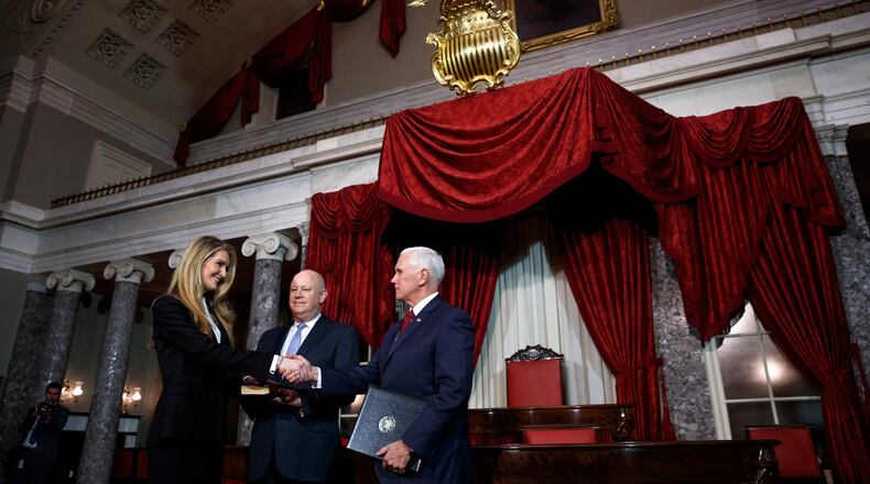 Sen. Kelly Loeffler, R-Ga., left, with her husband Jeffrey Sprecher, center, shakes hands with Vice President Mike Pence after a re-enactment of her swearing-in Monday, Jan. 6, 2020, in the Old Senate Chamber on Capitol Hill in Washington. (AP Photo/Jacquelyn Martin)